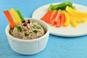 Adzuki bean dip with red, yellow and green bell pepper sticks on blue background