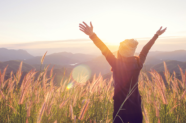 woman rise hand up on top of mountain and sunset sky