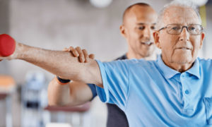 Personal trainer exercise helps senior man