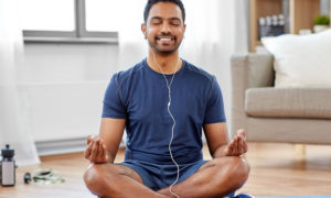 man in earphones listening to music on smartphone at home